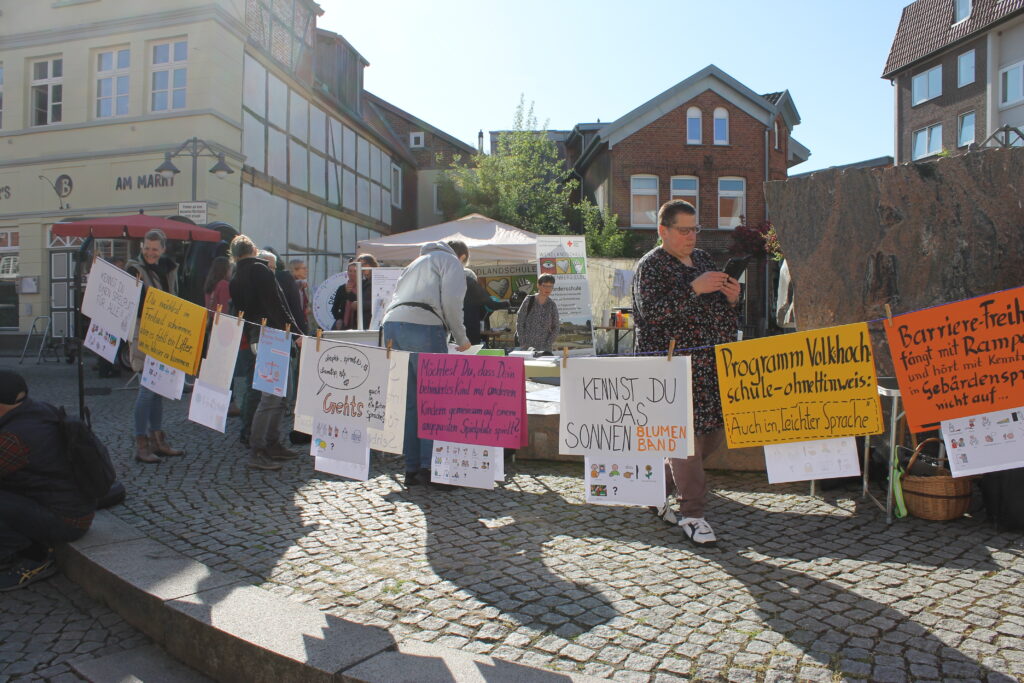 Auf dem Foto sind Plakate an einer Wäscheleine aufgehängt zu sehen. Auf den Plakate stehen verschiedene Fragen und Forderungen zum Thema Inklusion, die am 8. Mai während des Protesttages auf dem Marktplatz in Dannenberg präsentiert wurden.