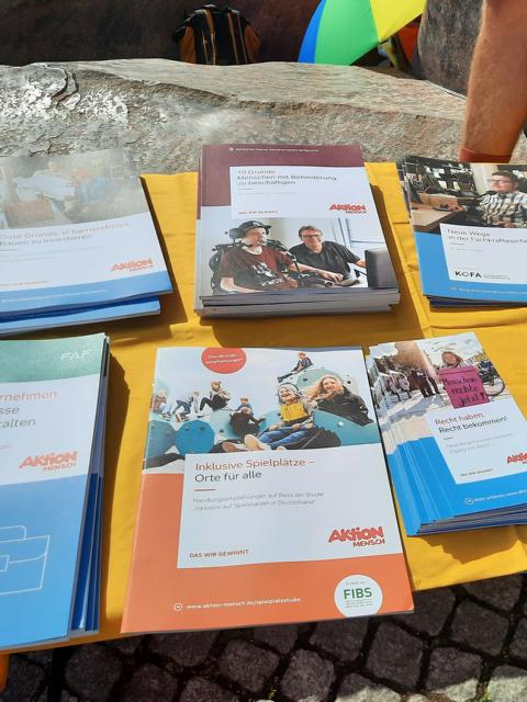 Auf dem Foto ist ein Tisch zu sehen, worauf verschiedene Informationsbroschüren zum Thema Inklusion liegen. Diese wurde am Aktionstag am 8. Mai ausgelegt und durften mit genommen werden.