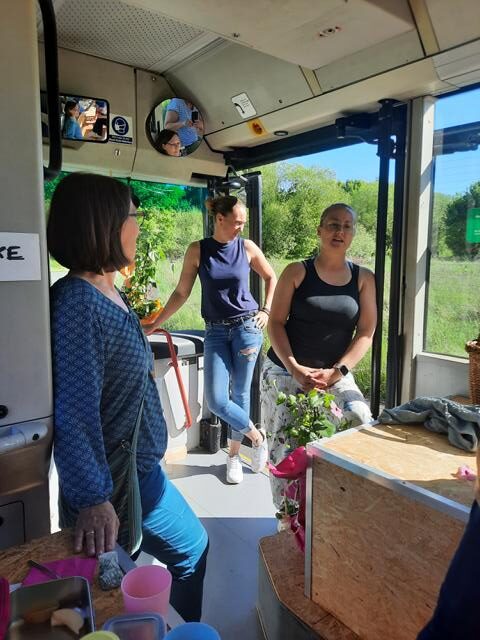 Auf dem Bild sind drei Personen zu sehen, die in dem alten Bus "Bernhard" stehen. Zwei unterhalten sich miteinander.