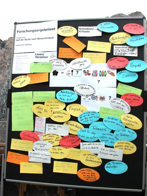 Auf dem Bild ist eine Stellwand zu sehen, worauf sehr viel Antworten stehen zu der Fragestellung: Auf der Such nach Menschlichkeit. Diese Kunstaktion vom erfundenen Institut für Hoffnung war am 8. Mai ein Teil der Protestaktion.
