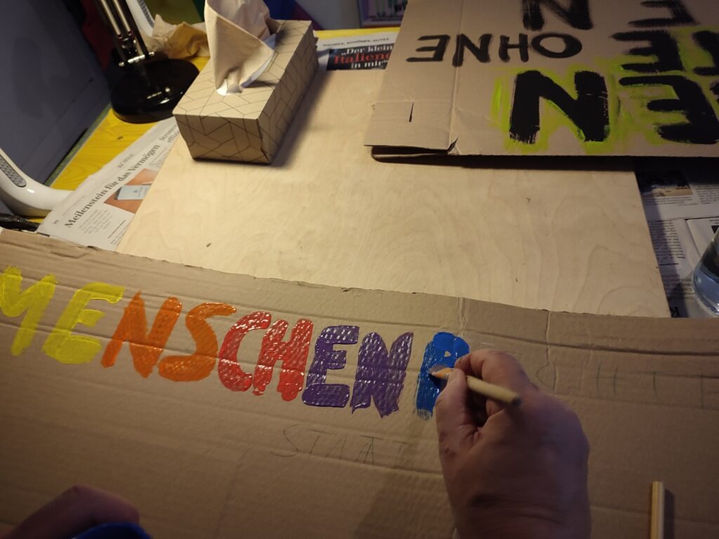 Eine Person malt ein Bild. Bis jetzt steht da Menschenr... der Pinsel setzt an für die nächsten Buchstaben.