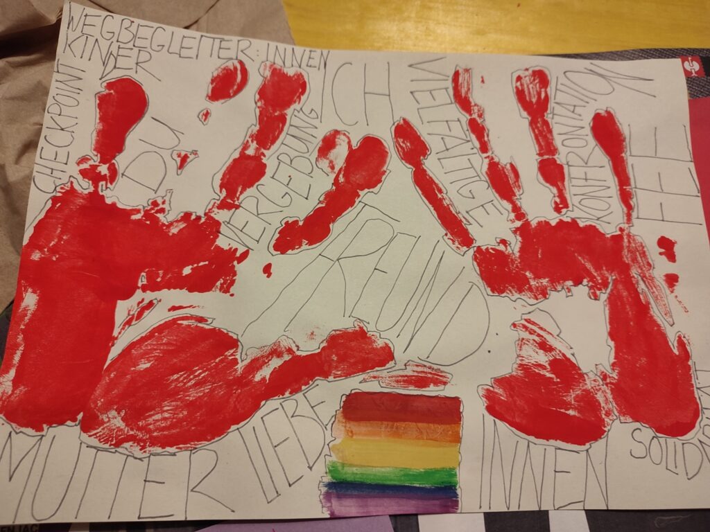 Ein Ergebnis ist ein Plakat. Auf dem sind zwei rote Hände und eine Regenbogenflagge. Ebenso stehen die Wörter: Mutter, Liebe, Freundinnen, Solidarität, Wegbegleiterinnen, Checkpoint, Kinder, du, Vergebung, Vielfältige Konfrontation und Fee. 